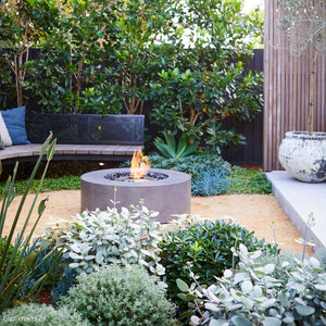 ecosmart fire ark gray fire pit table in a lush garden