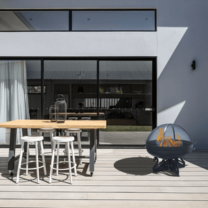 modern blaze round swan base steel fire pit in a cozy patio dining area