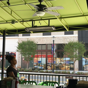 Black bromic tungsten smart-heat electric patio heater mounted overhead at a cafe