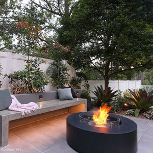 ecosmart fire ark black fire pit table in a lush garden setting