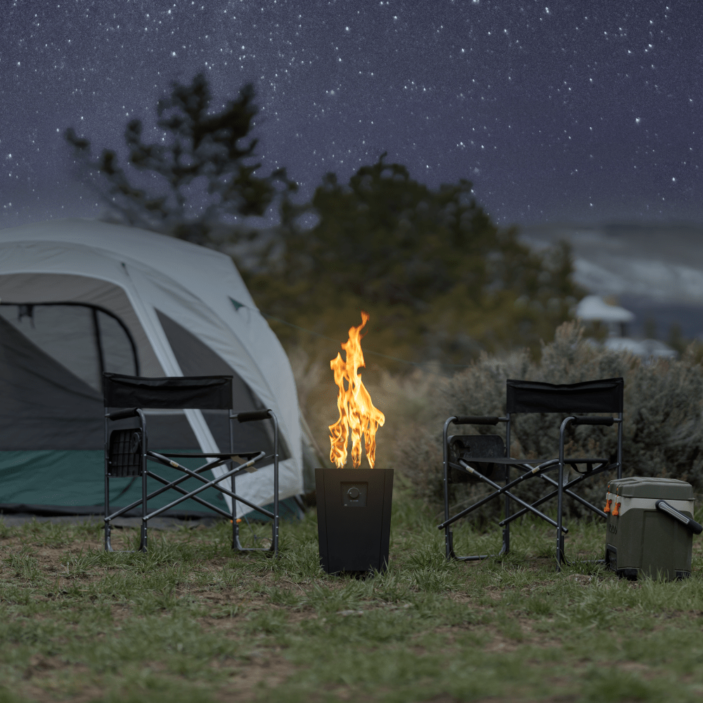 The Live Outdoor Firestorm Series I Free Standing Fire Pit with the burner on under a star-filled sky at the campsite.