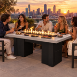 Friends enjoying tapas and cocktails on a rooftop terrace around a Top Fires Alameda 72-inch GFRC gas fire table with a Limestone tabletop and Black base