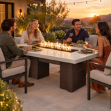 Friends sharing dinner around a Top Fires Alameda 72-inch GFRC gas fire table with a Limestone tabletop and Copper Vein base