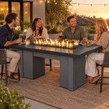 Friends sharing dinner around a Top Fires Alameda 72-inch GFRC gas fire table with a Smooth Black tabletop and Gray base