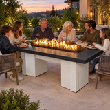 Family enjoying an evening meal around a Top Fires Alameda 72-inch GFRC gas fire table with a Smooth Black tabletop and White base