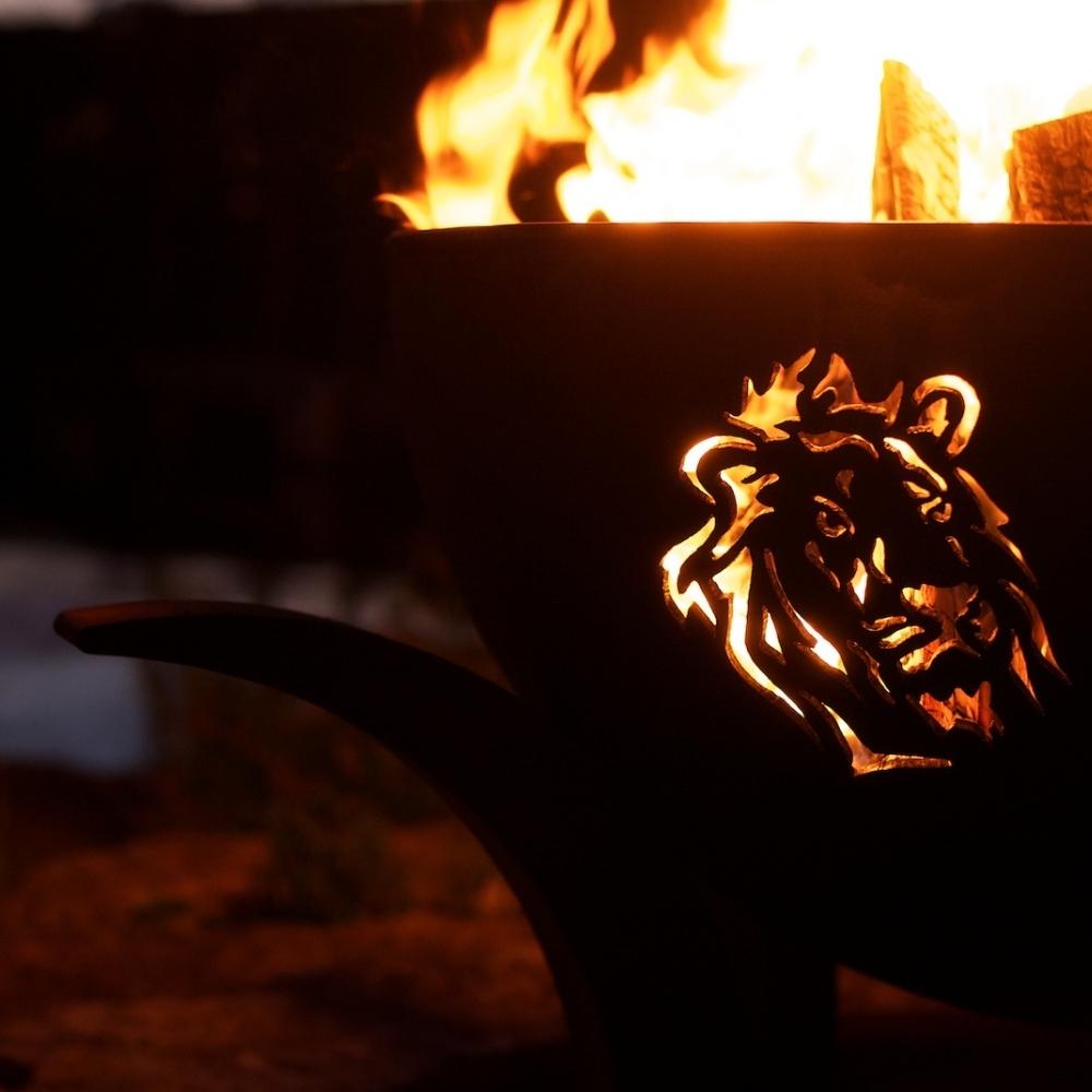 Lion Design of Fire Pit Art Africa's Big Five With Burning Logs - angle view