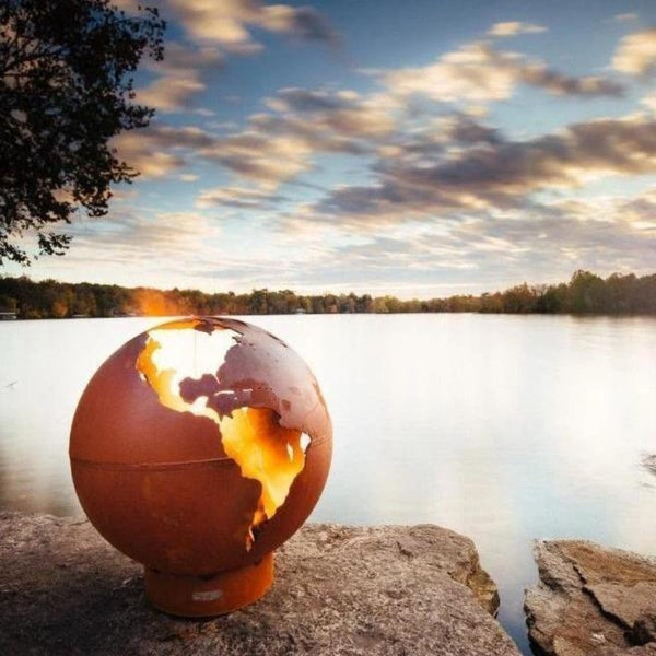 Fire Pit Art Third Rock - Globe Shaped 36" Handcrafted Carbon Steel Fire Pit (TR) Lit Up Beside A Lake