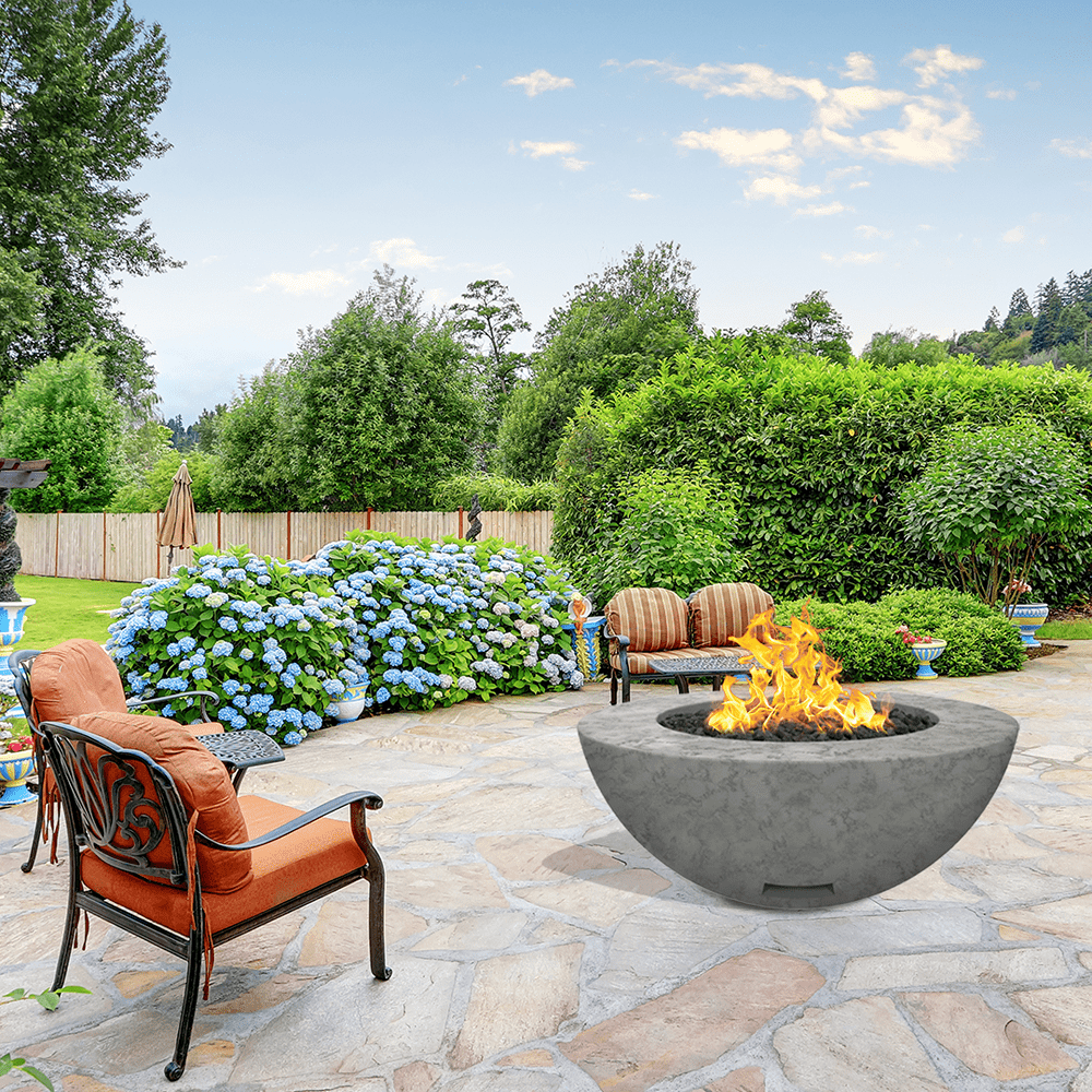 modern blaze round slate fire bowl with textured surface in a lush garden - angle view