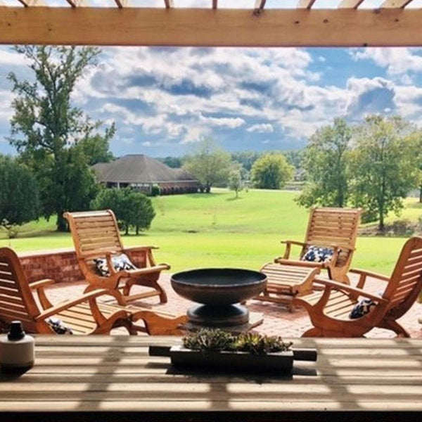Seasons Fire Pits Vulcan Round Steel Fire Pit near a pergola with wooden chairs