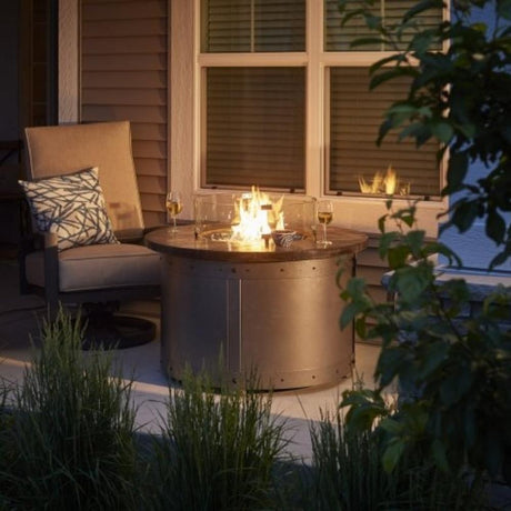 The Outdoor GreatRoom Company Edison 39-inch Round Gas Fire Pit Table in backyard